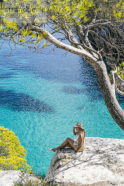 Reife Frau verbringt ihre Freizeit auf einem Felsen am Meer sitzend