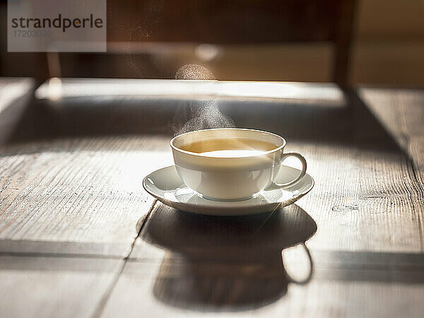 Tasse mit heißem grünem Tee auf einer Holzunterlage