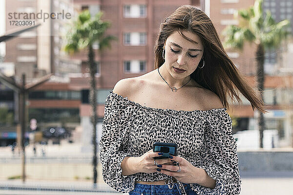 Junge Frau benutzt Smartphone in der Stadt
