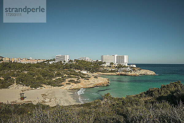 Spanien  Mallorca  Manacor  Klarer blauer Himmel über leerem Strand vor der Küstenstadt im Sommer
