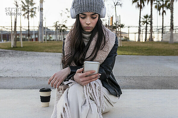 Schönes Teenager-Mädchen  das ein Smartphone benutzt  während es auf einer Bank im Park sitzt