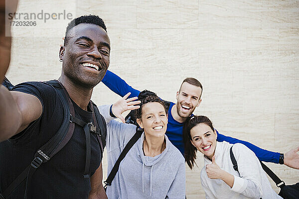 Fröhliche Athletenfreunde machen ein Selfie vor einer Wand