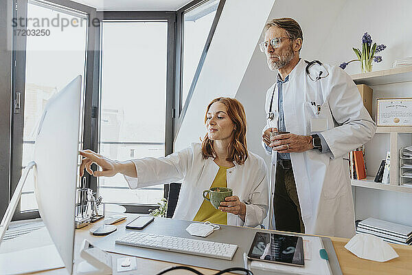 Ärzte trinken Kaffee  während sie in der Klinik am Computer arbeiten