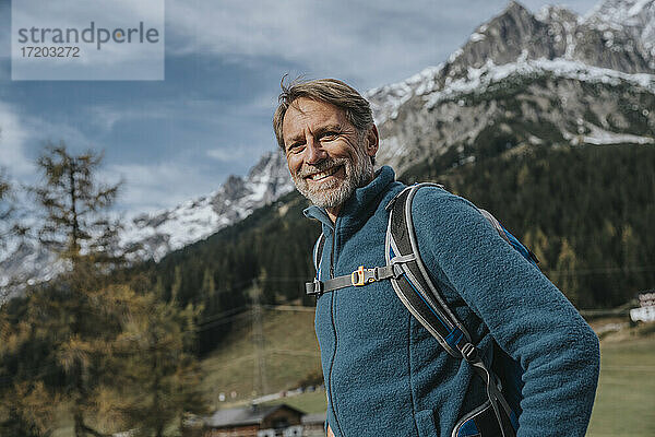 Lächelnder reifer Mann mit Rucksack vor dem Himmel am Hochkonig  Salzburger Land  Österreich