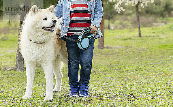 Junge hält Hund an der Leine in der Natur