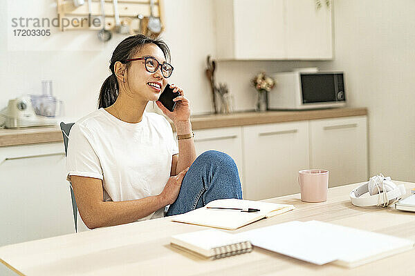 Junge Frau  die zu Hause sitzend mit ihrem Handy telefoniert