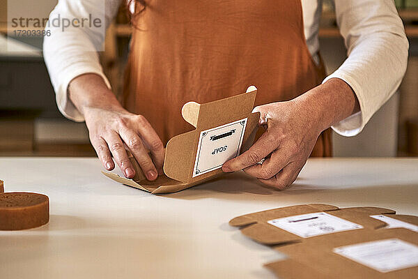 Eine Frau verpackt in einer Werkstatt handgemachte Seife in Schachteln