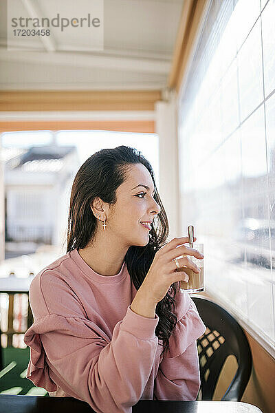 Schöne Frau mit Tasse schaut durch das Fenster in einem Café