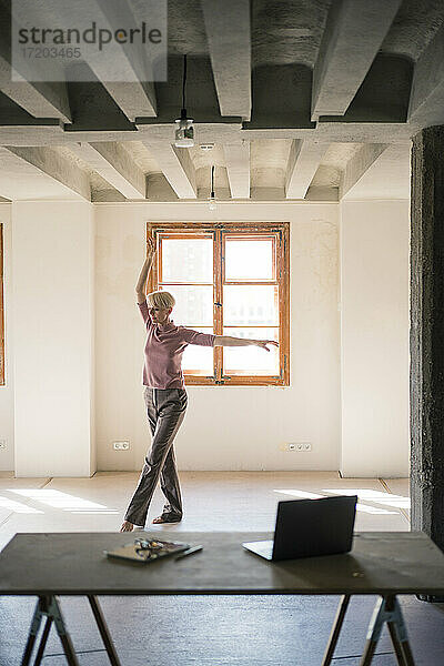 Frau tanzt gegen Fenster in Loftwohnung
