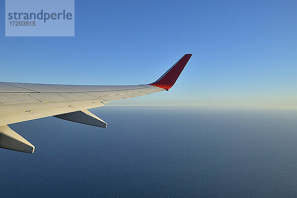Tragfläche eines Verkehrsflugzeugs gegen einen klaren blauen Himmel