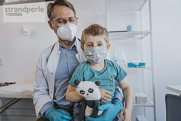 Arzt und Patient mit Gesichtsschutzmaske in der Klinik sitzend
