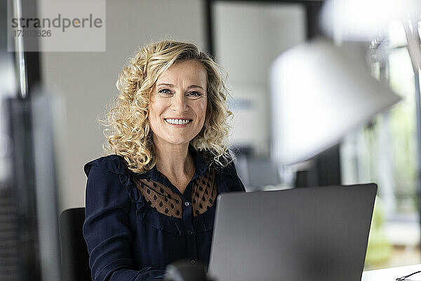 Schöne lächelnde Unternehmerin mit Laptop im Büro