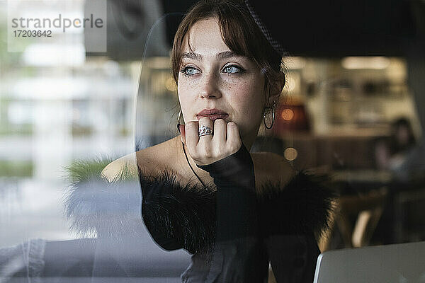 Schöne Geschäftsfrau mit blauen Augen  die durch das Fenster eines Cafés schaut