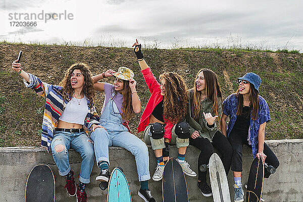 Glückliche Freundinnen  die ein Selfie mit ihrem Handy an einer Stützmauer machen