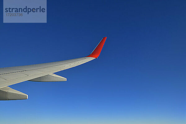 Tragfläche eines Verkehrsflugzeugs gegen einen klaren blauen Himmel