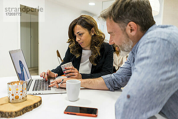 Männliche und weibliche Unternehmer planen ihre Strategie am Laptop  während sie in der Lobby ihres Büros sitzen