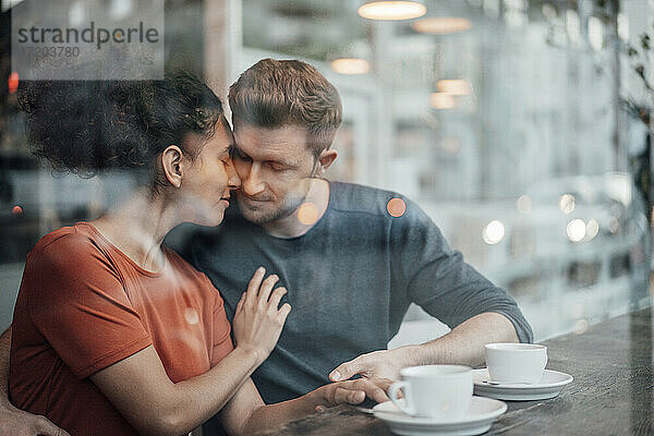 Paar sitzt mit geschlossenen Augen in einem Café von Angesicht zu Angesicht