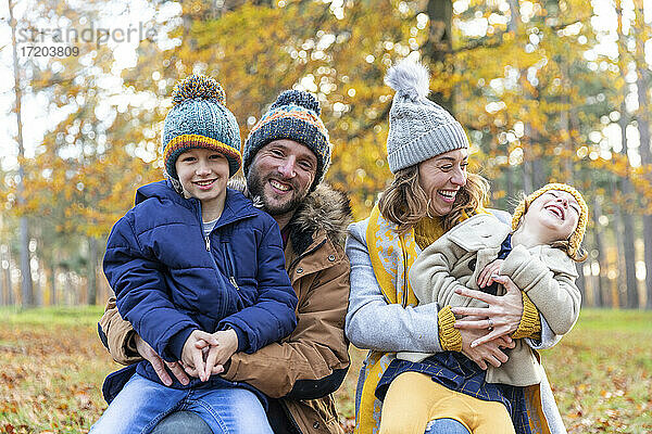 Fröhliche Eltern  die lächelnd mit ihren Kindern im Wald sitzen
