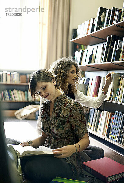 Studentinnen lesen Bücher  während sie in der Bibliothek sitzen
