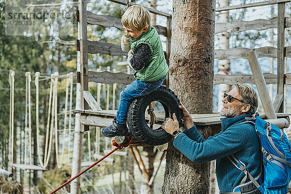 Glücklicher Vater mit Sohn beim Hochseilgarten im Wald im Salzburger Land  Österreich