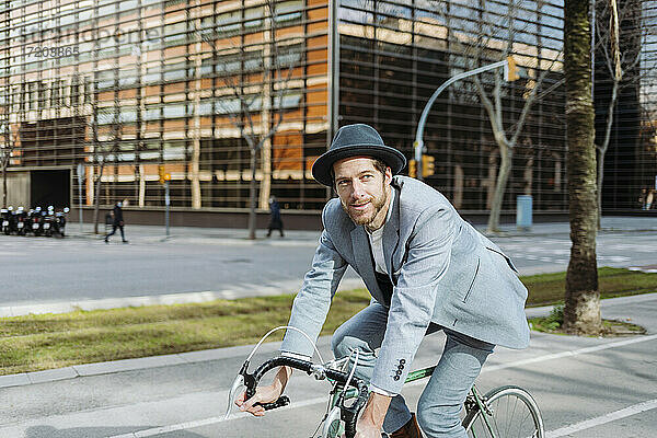 Geschäftsmann mit Hut auf dem Fahrrad in der Stadt