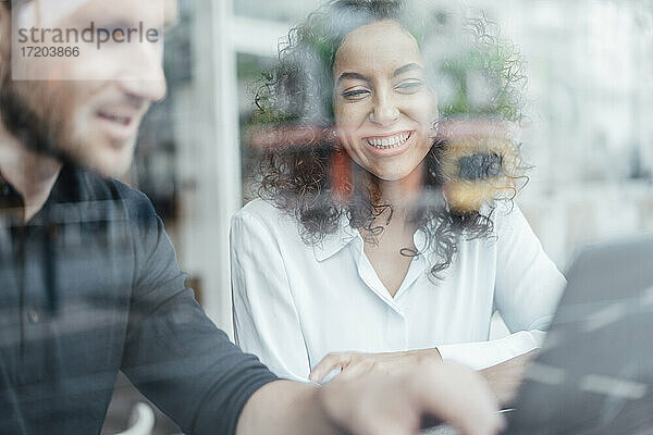Geschäftsfrau lächelt bei der Arbeit mit einem Kollegen in einem Cafe