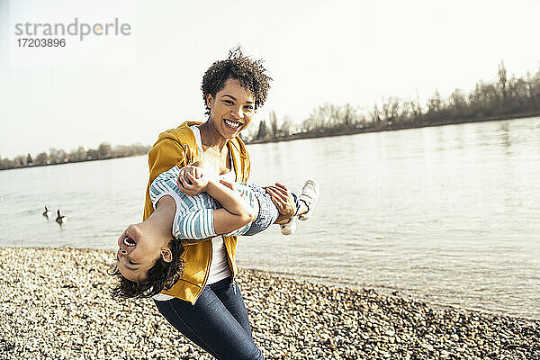 Glückliche Frau mit Sohn beim Spielen am See an einem sonnigen Tag
