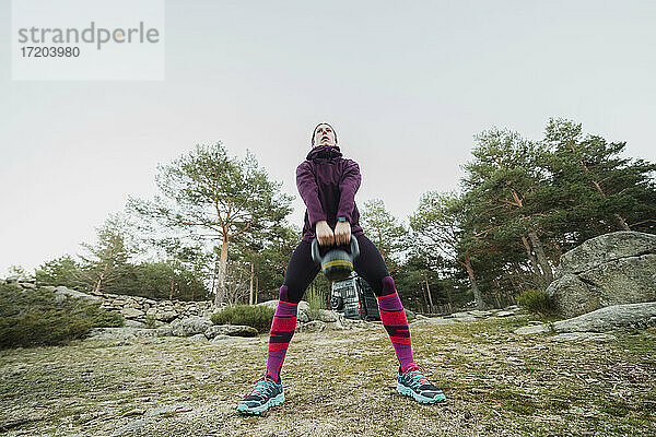 Frau trainiert mit Kettlebell im Wald