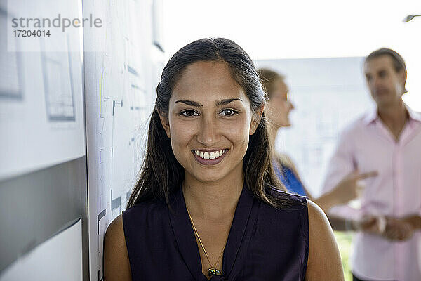 Lächelnde Architektin vor einer weißen Tafel im Büro
