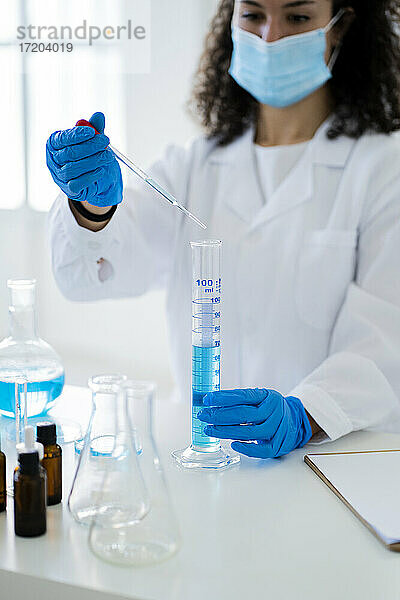 Eine Forscherin mischt eine chemische Lösung in einem Reagenzglas mit einer Pipette im Labor