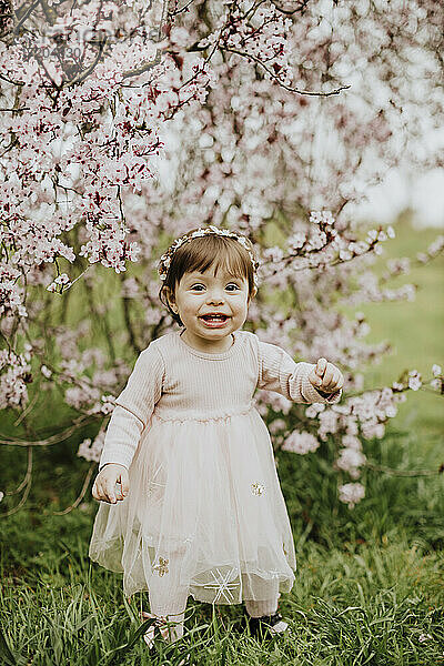 Baby Mädchen spielt mit Blumen von Kirschbaum im Frühling
