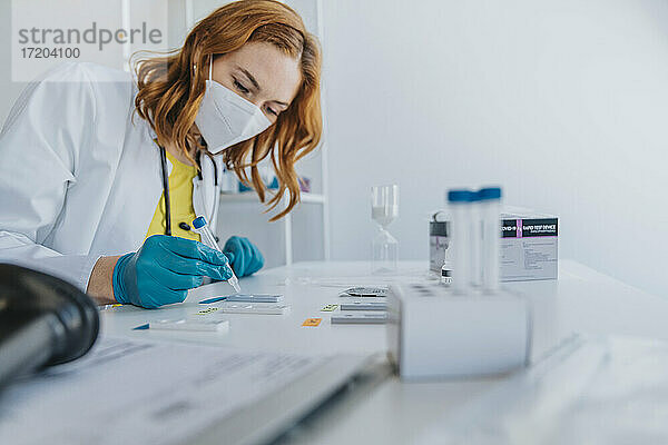 Mitarbeiter des Gesundheitswesens bei der Überprüfung von Proben auf Testkassetten im Untersuchungsraum
