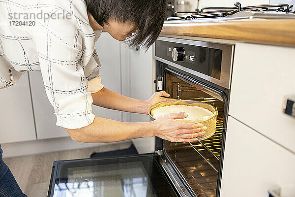 Frau schiebt einen Käsekuchen in den Ofen