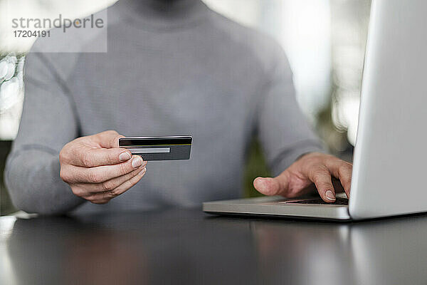 Geschäftsmann die Hände online bezahlen durch Kreditkarte auf Laptop im Büro