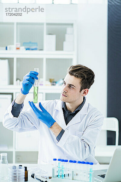Männlicher Wissenschaftler hält einen Messzylinder im Labor
