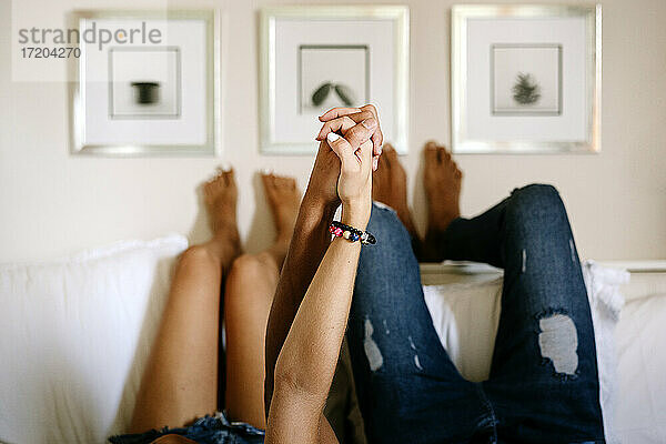 Ehemann und Ehefrau halten sich an den Händen  während sie auf dem Bett liegen