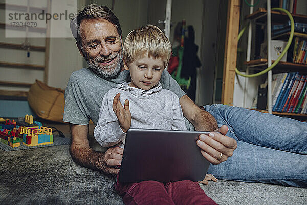 Glücklicher Vater und Sohn führen Videogespräche über ein digitales Tablet zu Hause