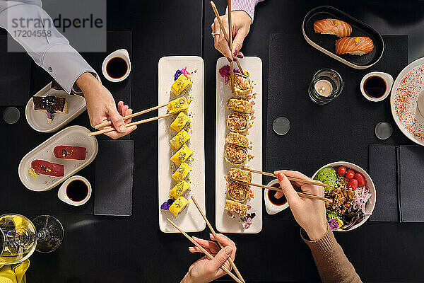 Weibliche Kunden essen frische Sushi mit Stäbchen im Restaurant