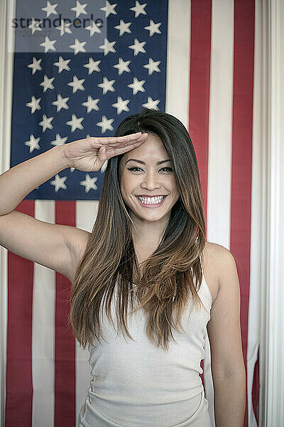 Schöne Frau salutiert vor der amerikanischen Flagge