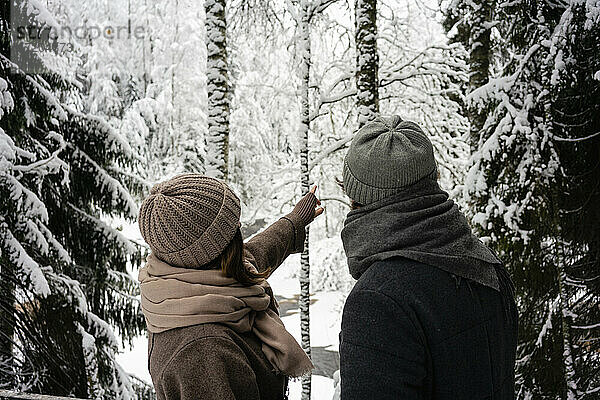 Freundin  die auf einen Baum zeigt  während sie neben ihrem Freund im Wald steht
