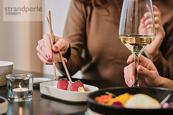 Junge Frauen essen Sushi und trinken Wein im Restaurant