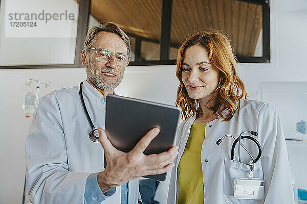 Mitarbeiter des Gesundheitswesens arbeiten im Stehen über ein digitales Tablet in einer Klinik