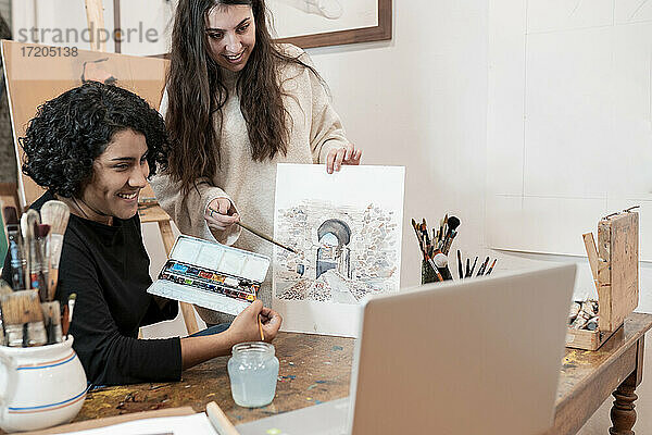 Künstlerinnen zeigen Gemälde während eines Videogesprächs im Atelier