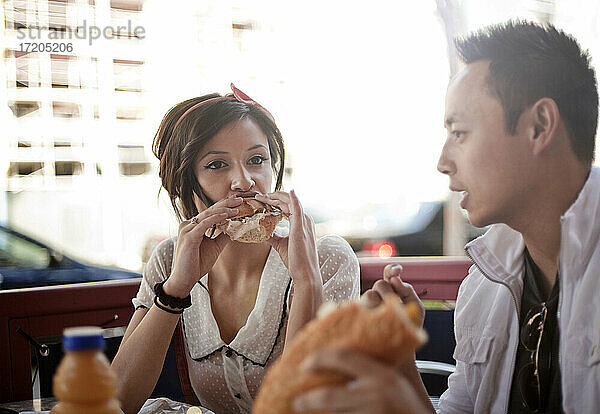 Schöne Frau und gut aussehender Mann essen Sandwich in einem Straßencafé