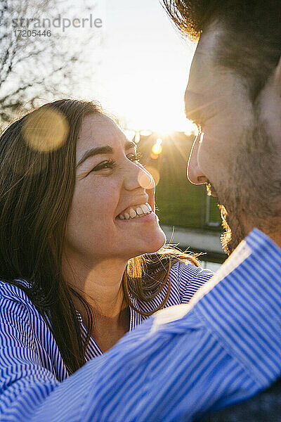 Lächelndes erwachsenes Paar  das sich bei Sonnenuntergang ansieht