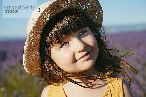 Porträt eines süßen kleinen Mädchens mit Strohhut  das im Freien steht