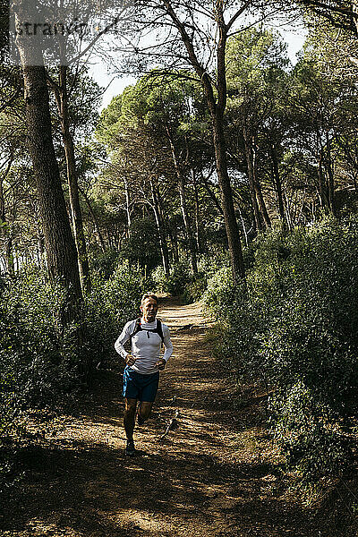 Mann läuft auf unbefestigtem Weg im Wald