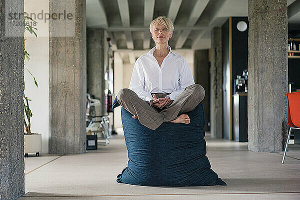 Geschäftsfrau meditiert auf Sitzsack zu Hause