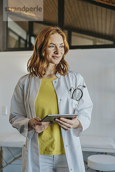 Allgemeinmediziner mit digitalem Tablet in der Klinik stehend