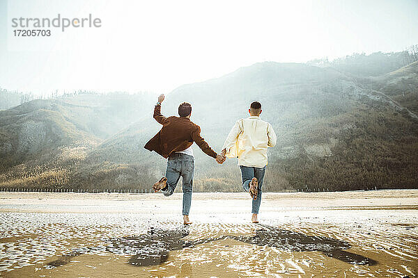 Homosexuelles Paar hält Hände und läuft am Strand
